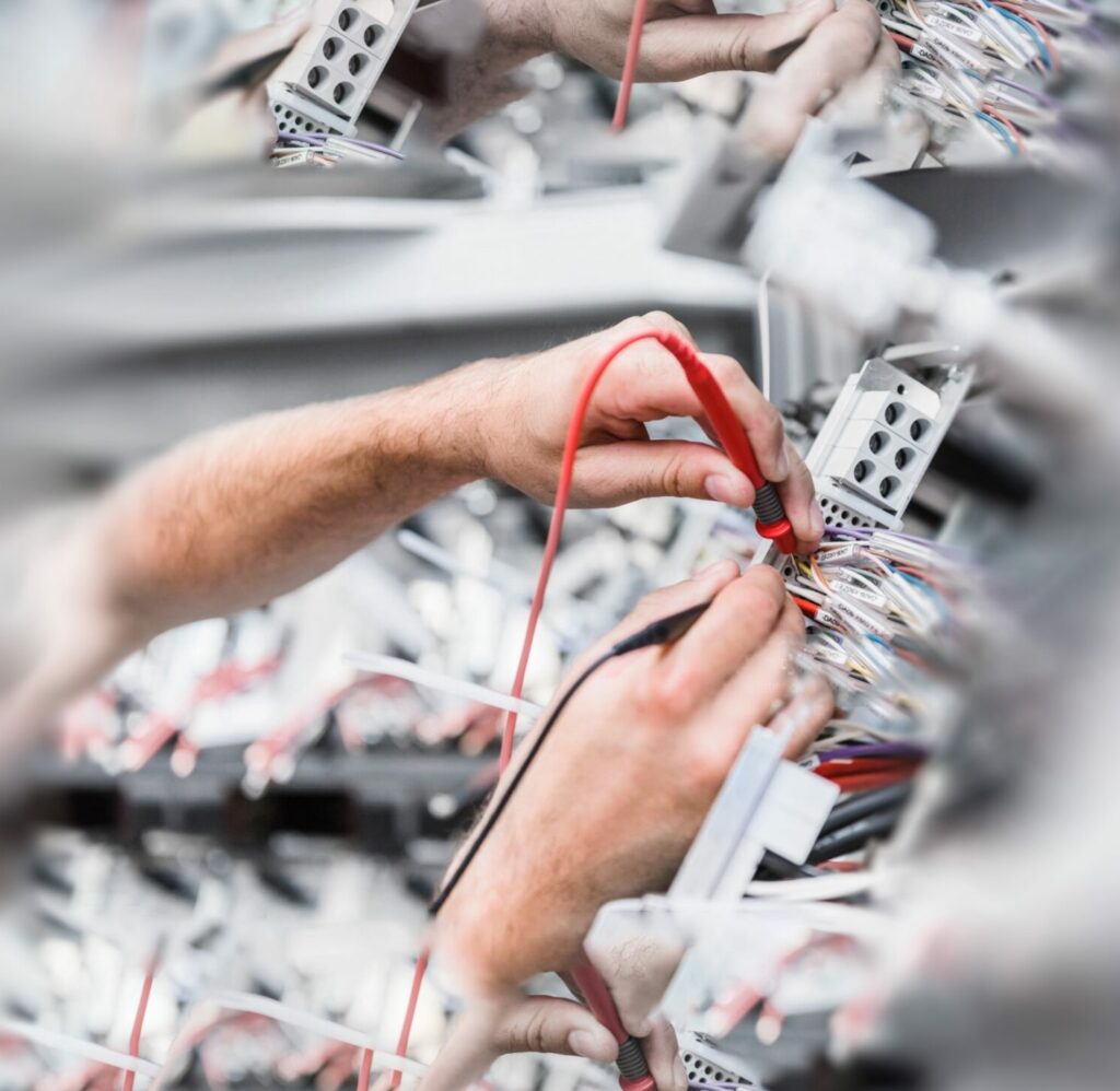 Hand prüft Spannungen an einem Verteiler
